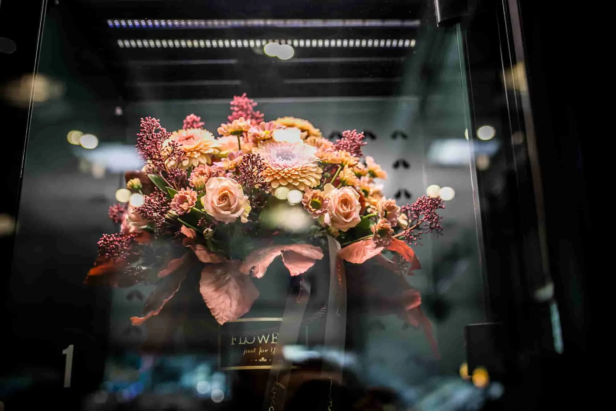 Premium-Blumenstrauß in einem beleuchteten Automatenfach mit sichtbar viel Platz an den Seiten